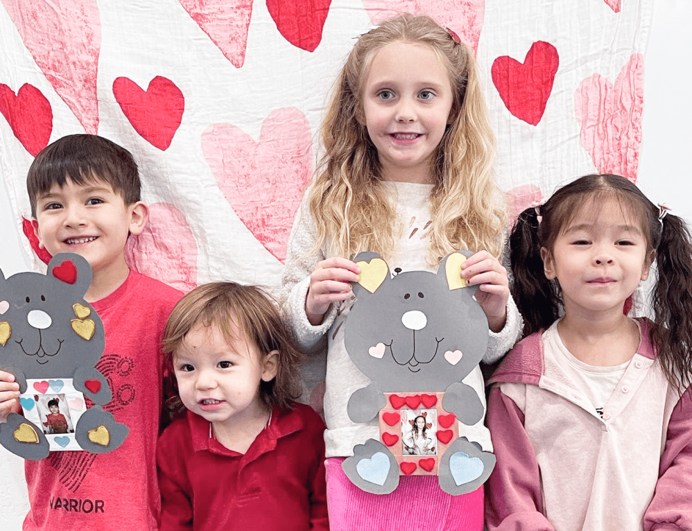 Four cute children holding their Valentine artwork.